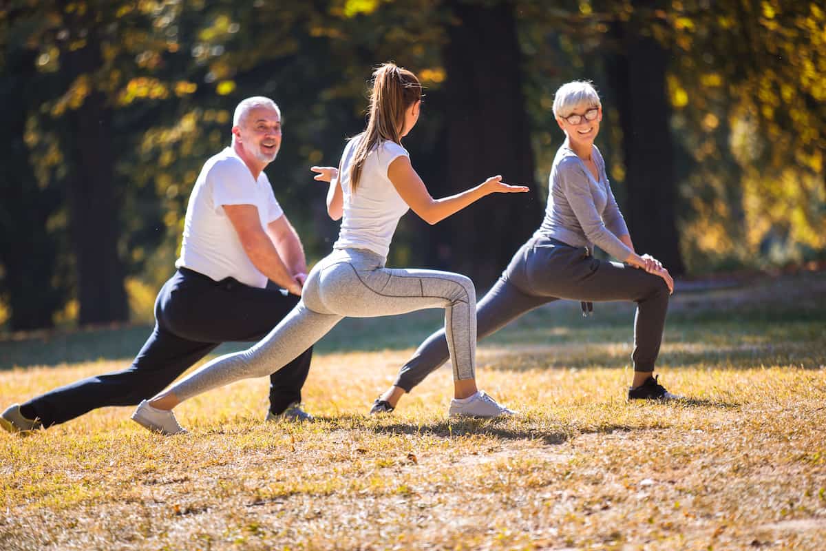 Getting fit after 50. Senior man and woman and young female instructor workout on fresh air.